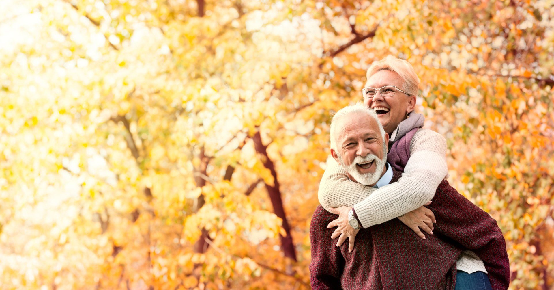 A man is carrying a woman on his back in a park.