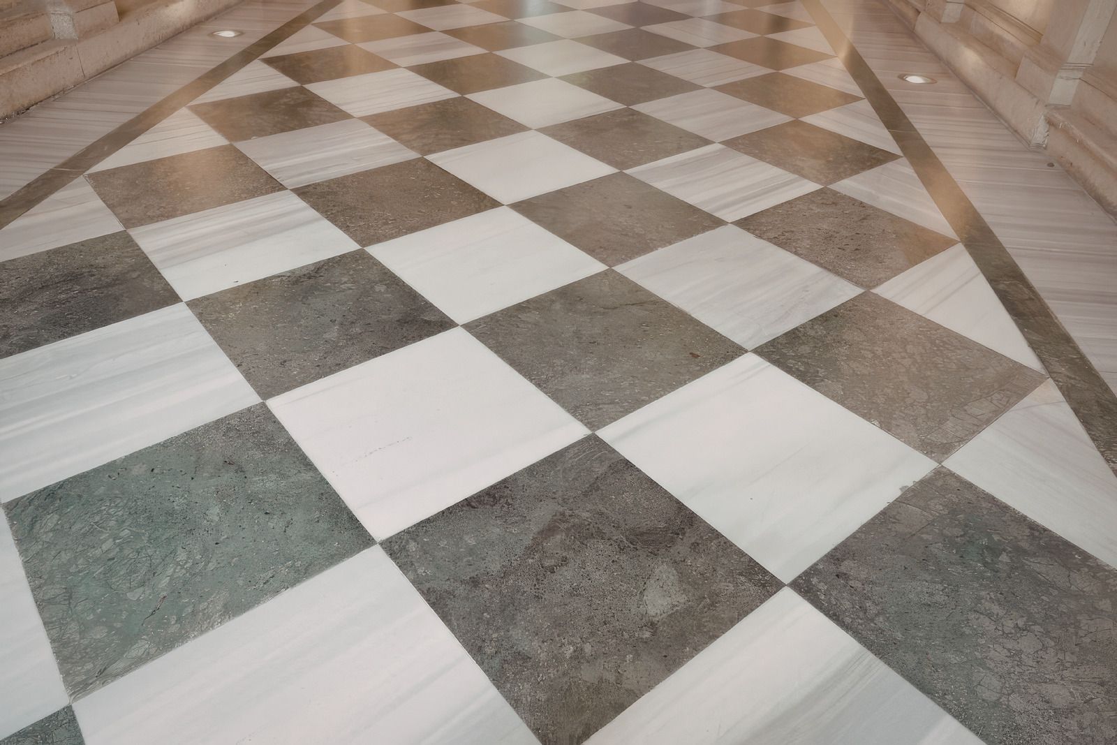 Black-and-white checkered marble floor in a hallway with stone walls