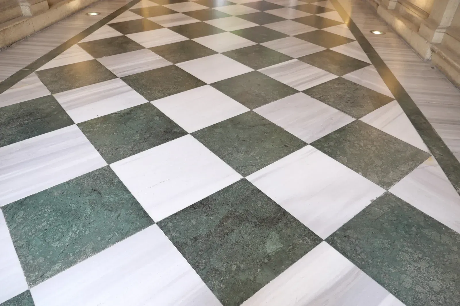 White and green checkered marble floor in a corridor, viewed in perspective.