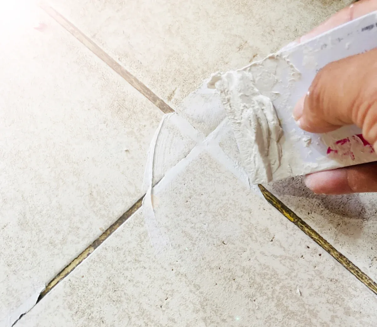 Blue-gloved hand spraying cleaner onto wet, tiled pavement