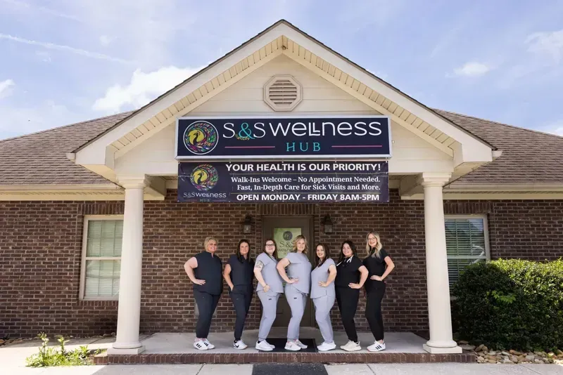 S&S Wellness Hub storefront with six staff standing under the entrance sign