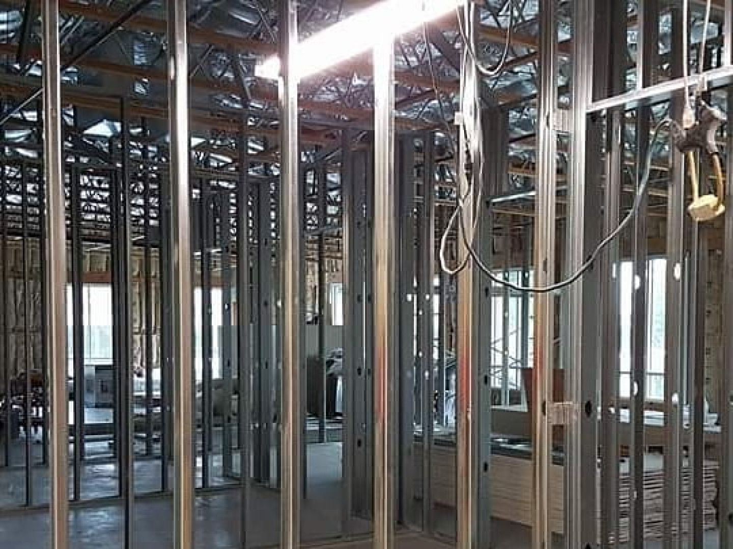 Bare interior of a framed building under construction with exposed metal studs and wiring.
