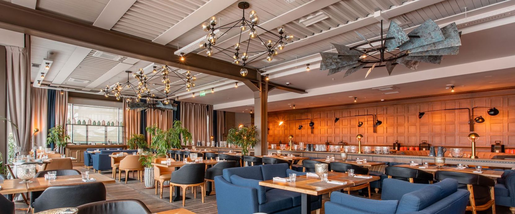 Modern restaurant interior with blue booths, warm lighting, and exposed ceiling beams