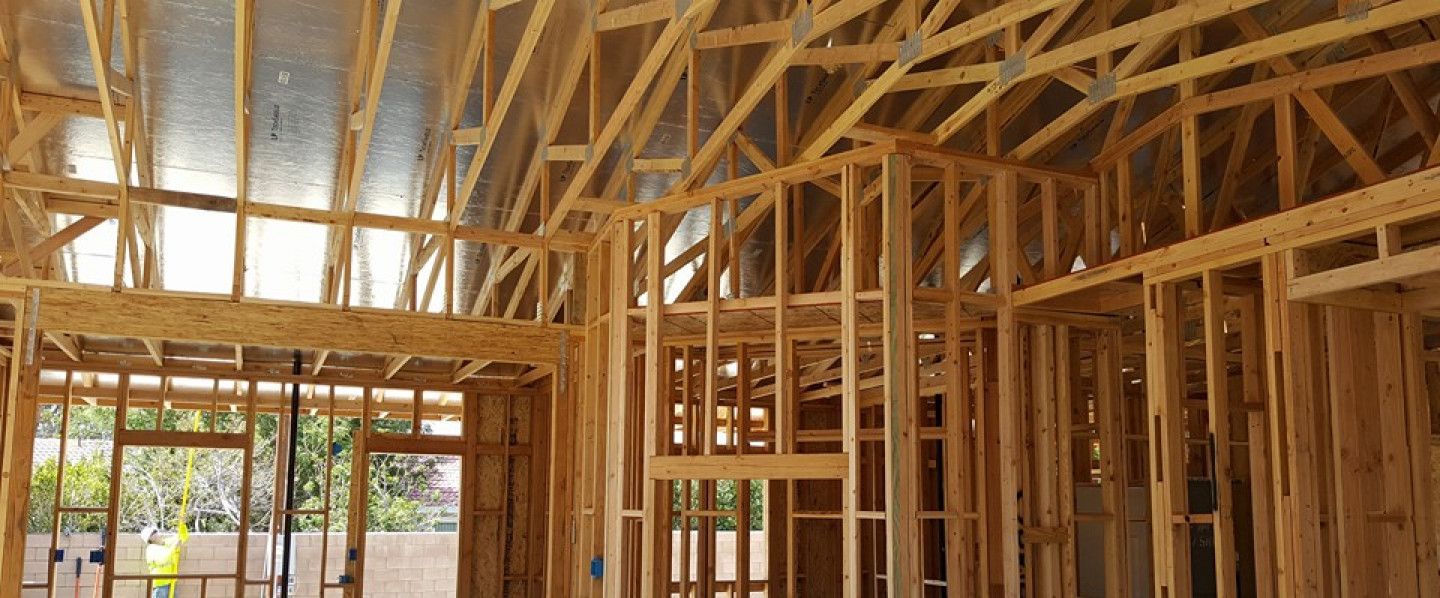 Wood-framed house interior under construction with exposed beams and open window and door framing