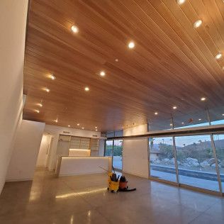 Spacious empty lobby with wood ceiling, white walls, large windows, and a floor cleaner in the center.