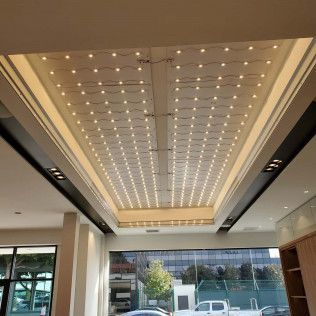 Modern lobby ceiling with rows of recessed lights and a large windowed entrance
