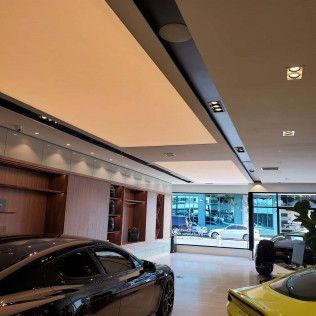 Luxury car showroom with two sports cars, wood accents, and large windows.