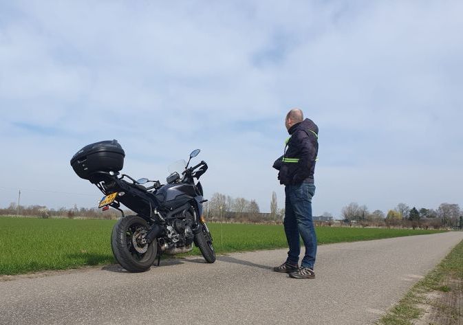 Aan de kant van de weg staat een man naast een motorfiets. Chris Gieling Coaching en Training