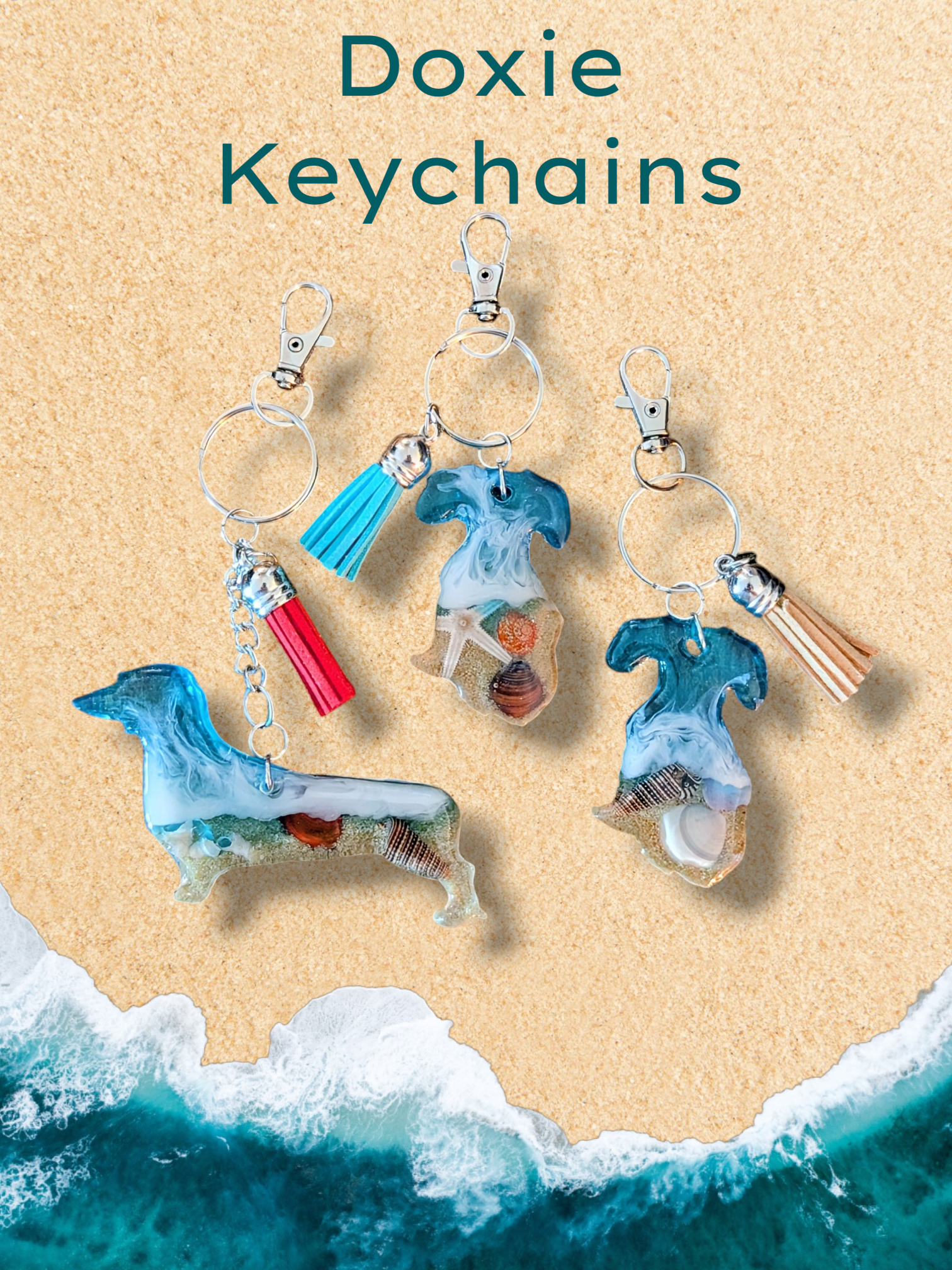 Doxie keychains on a sandy beach with a turquoise ocean. Some have tassels and ocean-themed decorations.