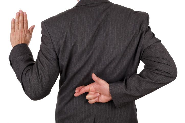 Person in a suit taking an oath with fingers crossed behind their back.