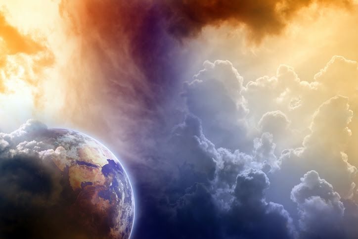 Planet Earth emerging from colorful clouds, orange and blue hues.