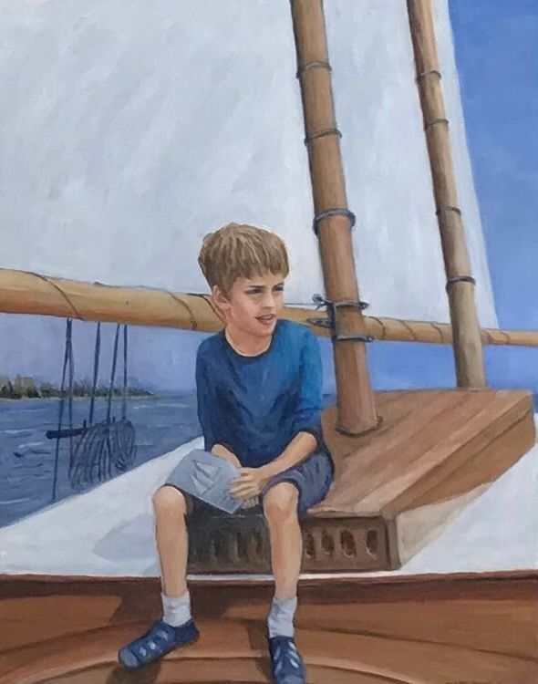 Boy sitting on a sailboat deck beside a mast, wearing a blue shirt and shorts, with the sea in the background