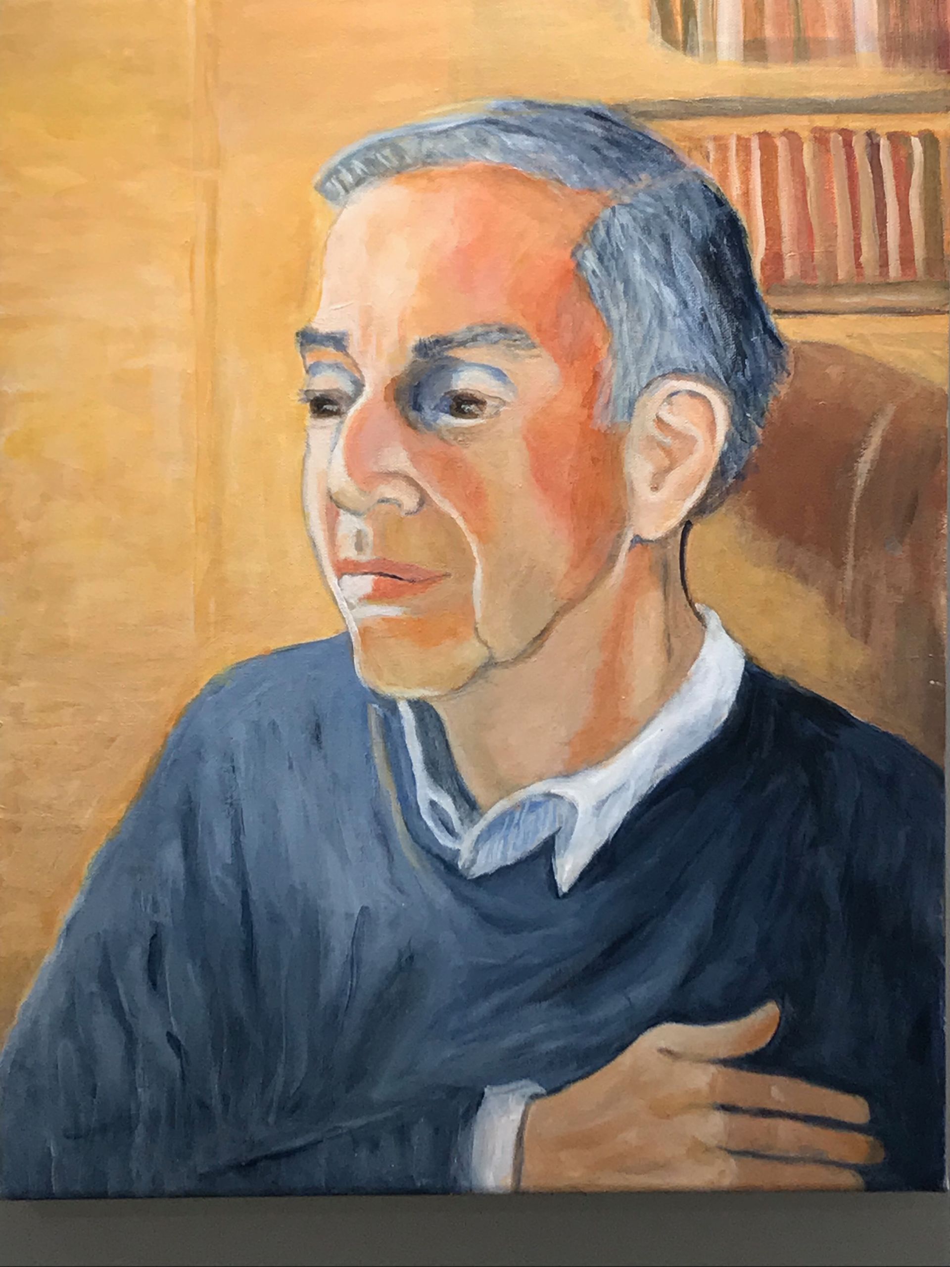 Portrait of a person in a dark sweater against a warm-toned background, looking left with a calm expression