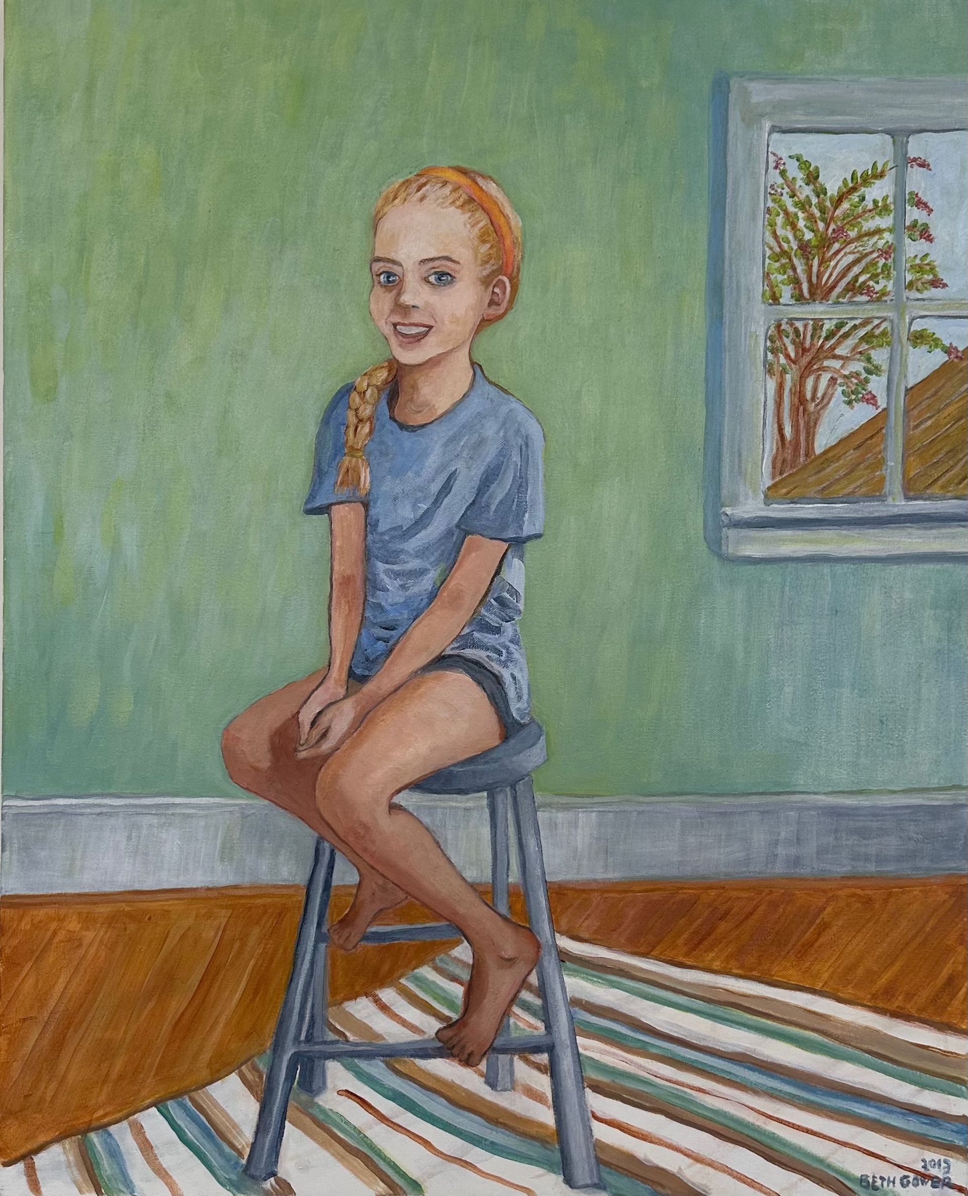 Person in blue shirt seated on a stool in a room with green walls, striped rug, and window