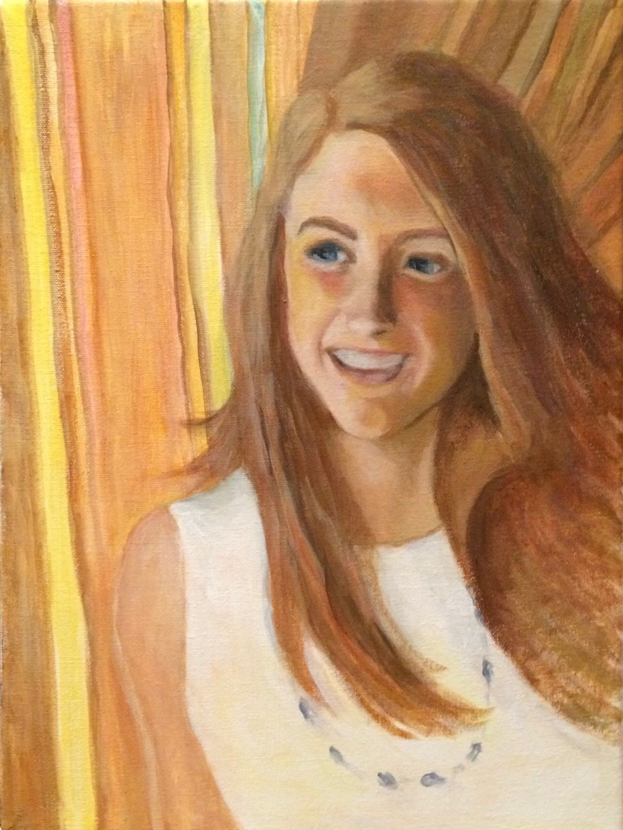 Portrait of a smiling person with long auburn hair in a white top against a warm striped background
