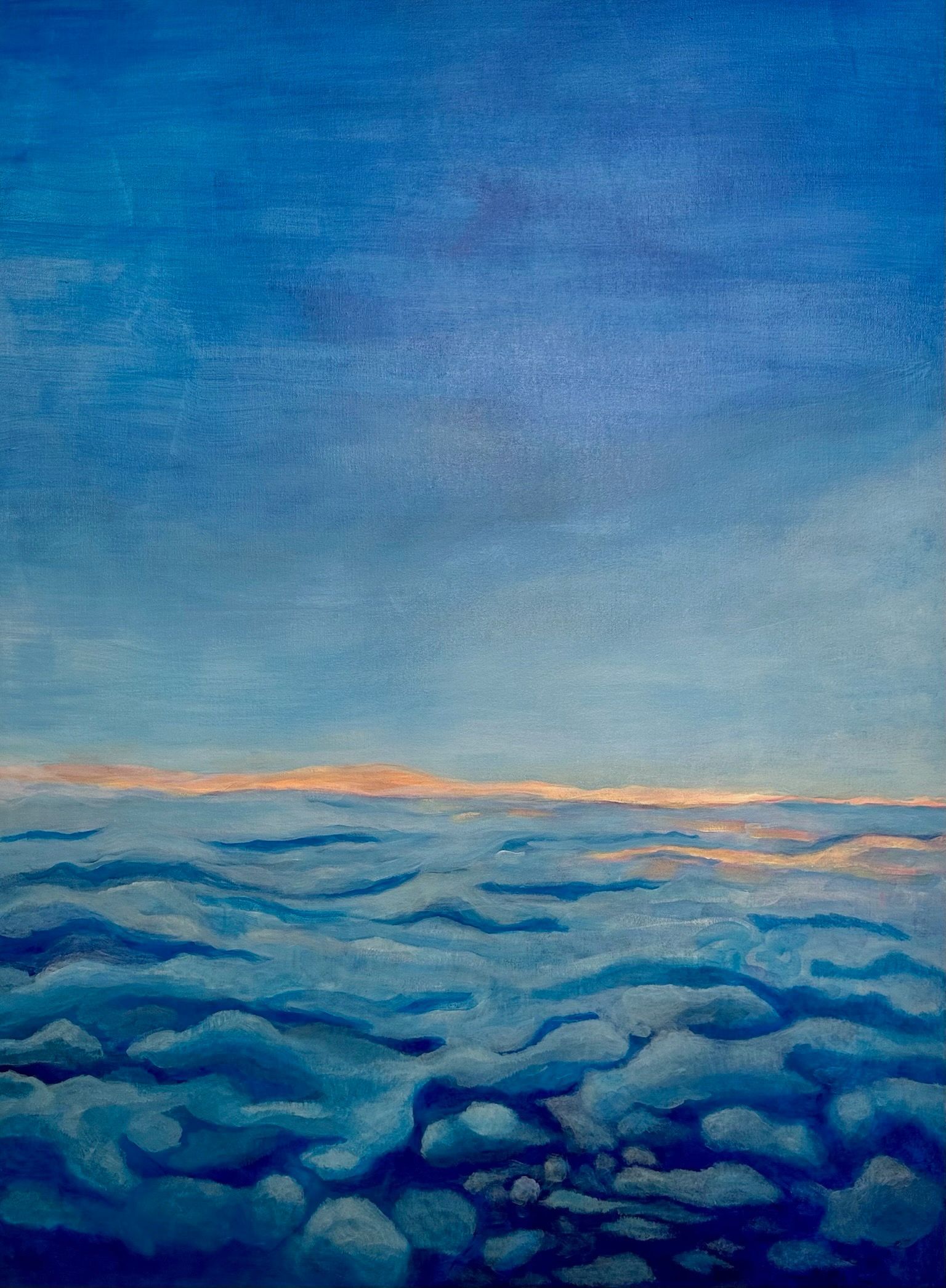 Blue sky above soft clouds at sunrise with a faint orange horizon