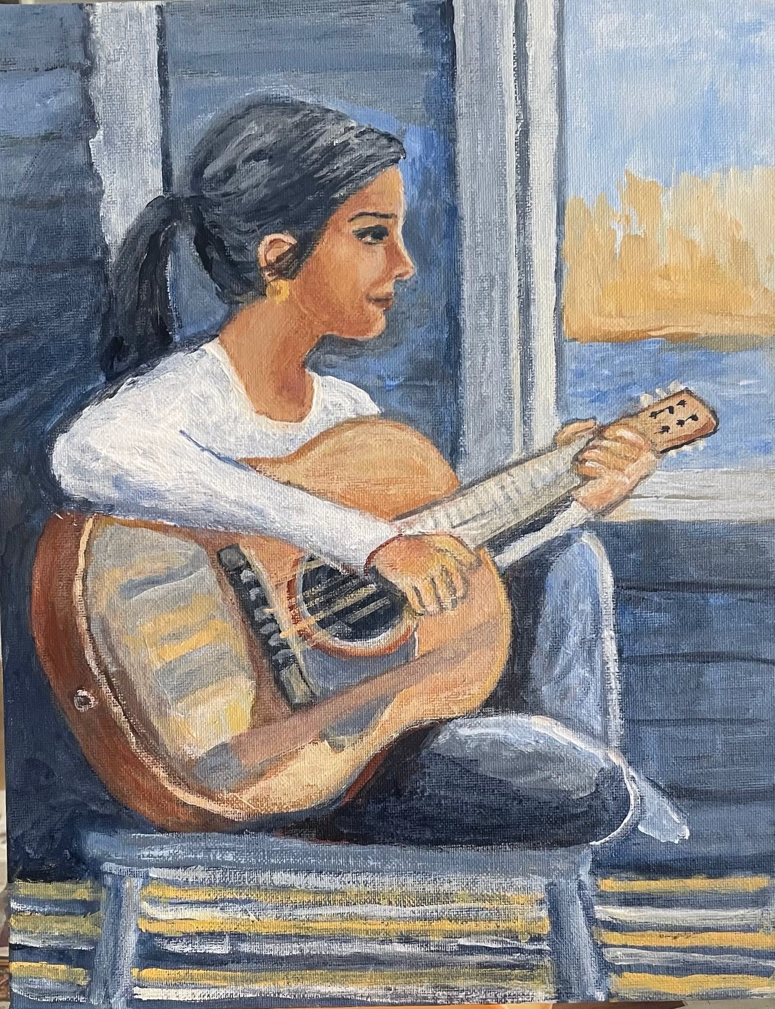 Person playing guitar while seated by a window, with blue walls and warm light outside.