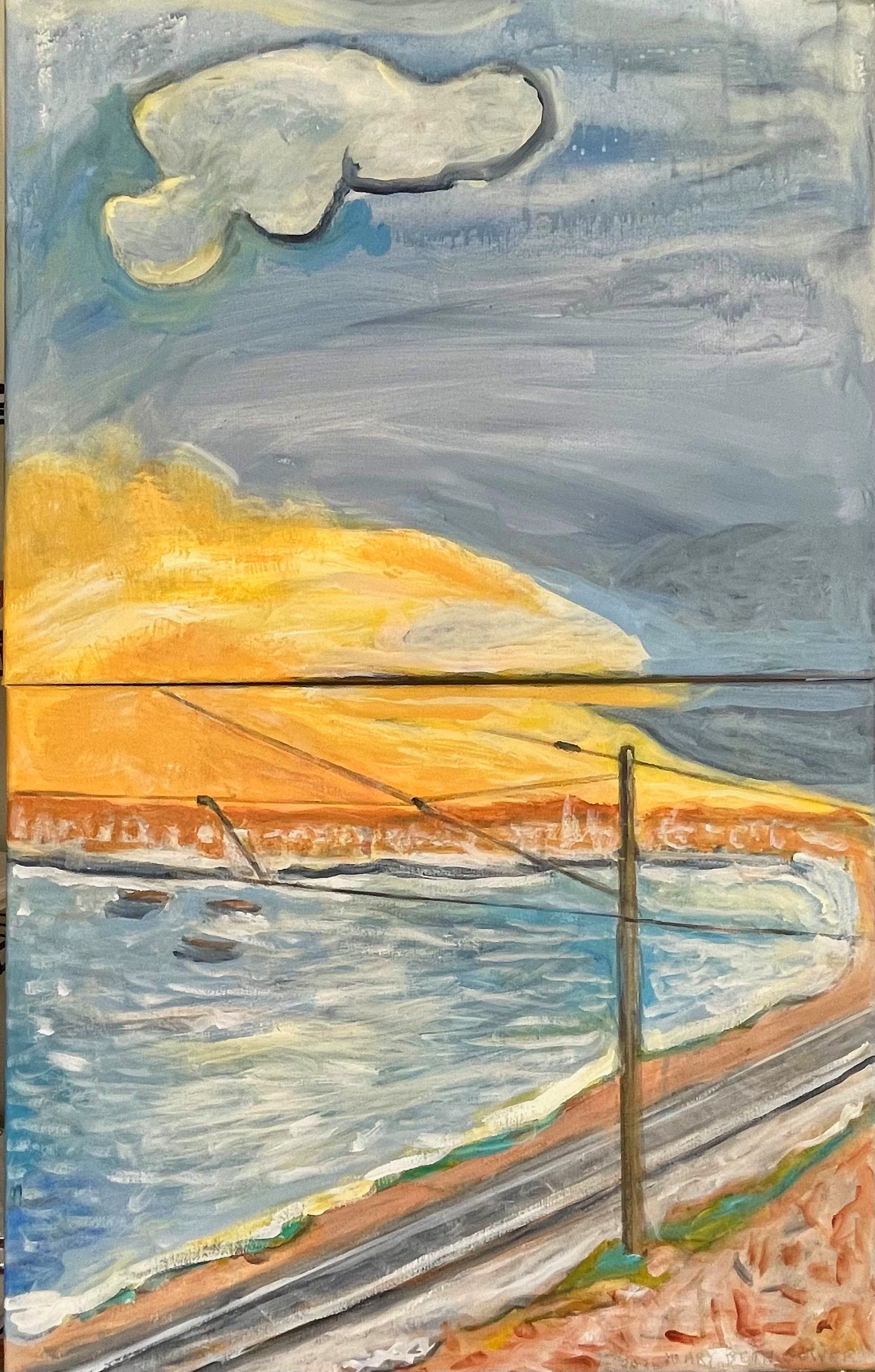 Waterfront railway beside blue water at sunset, with a pole and distant hills under a cloudy sky