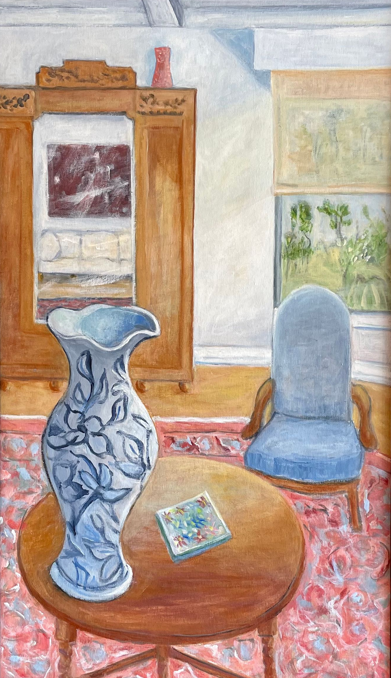 Blue ceramic vase on a wooden table in a softly lit room with a mirror, chair, and window in the background