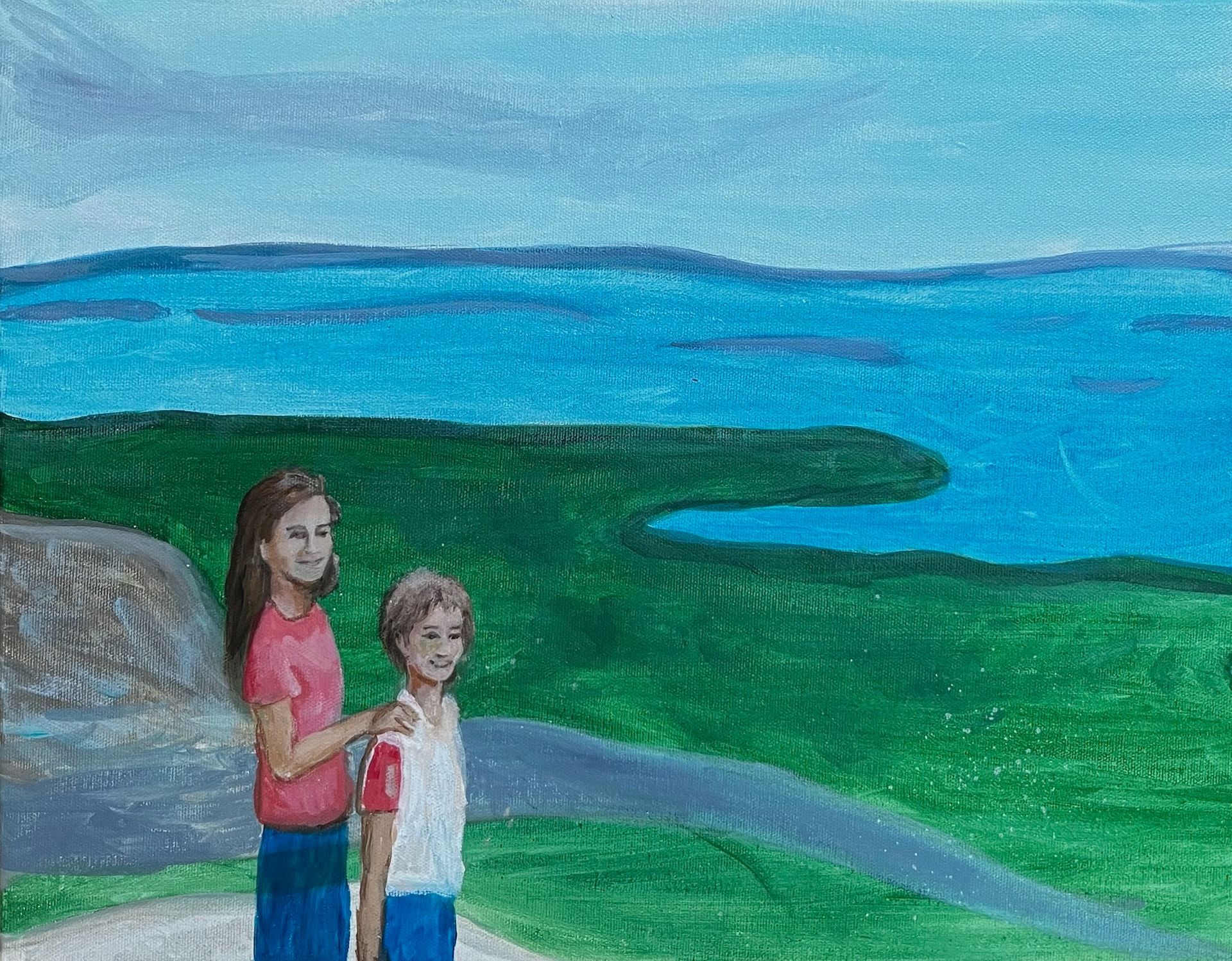 Two children standing by a green hill and blue water under a cloudy sky