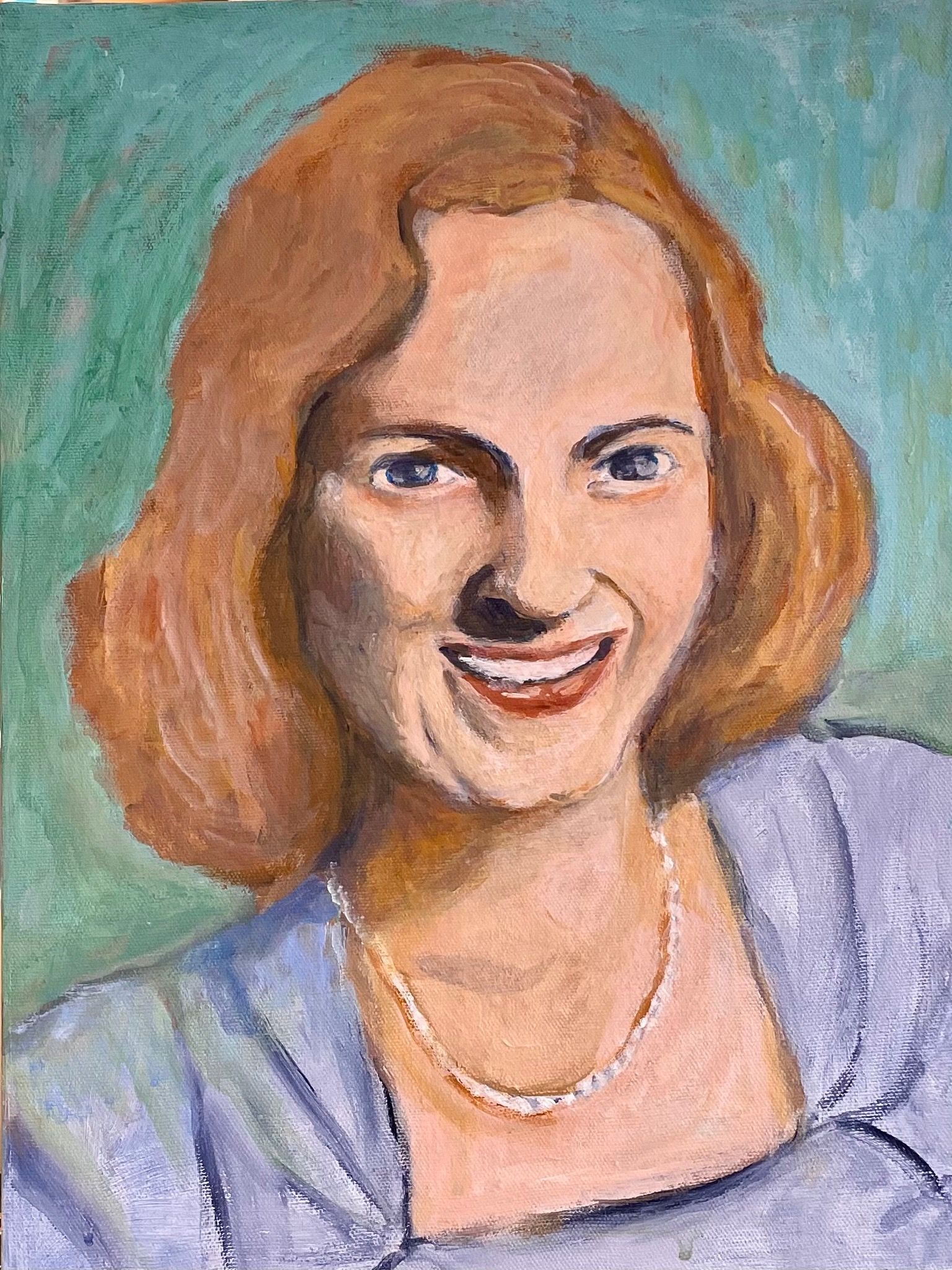 Portrait of a smiling woman with auburn hair in a lavender top against a teal background