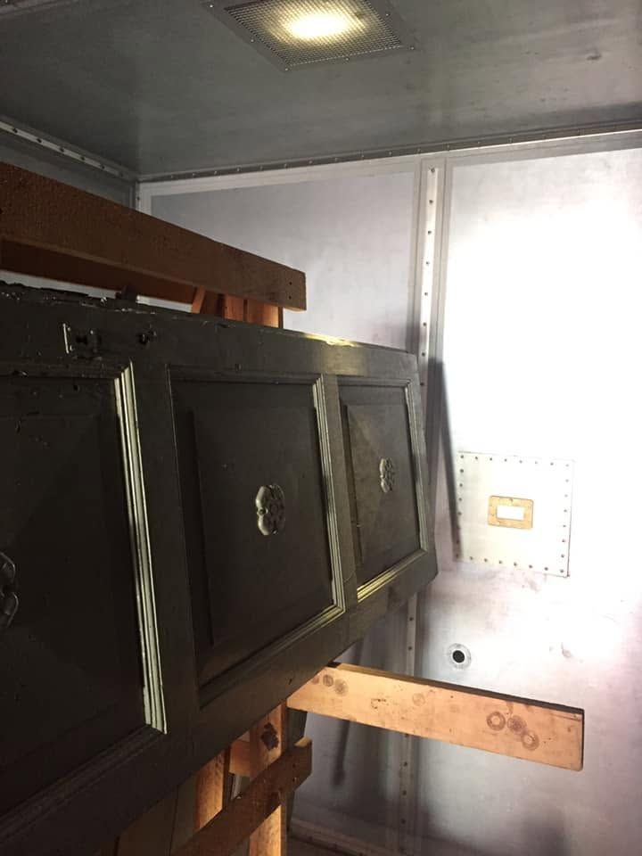 Armadi in legno scuro e una mensola a parete all’interno di un piccolo ripostiglio o vano di un veicolo.