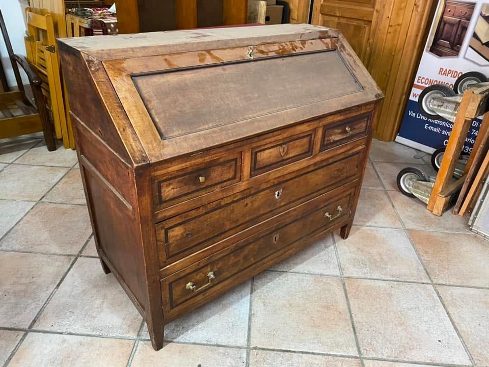 Scrivania in legno con piano inclinato e cassetti, in un laboratorio o showroom piastrellato