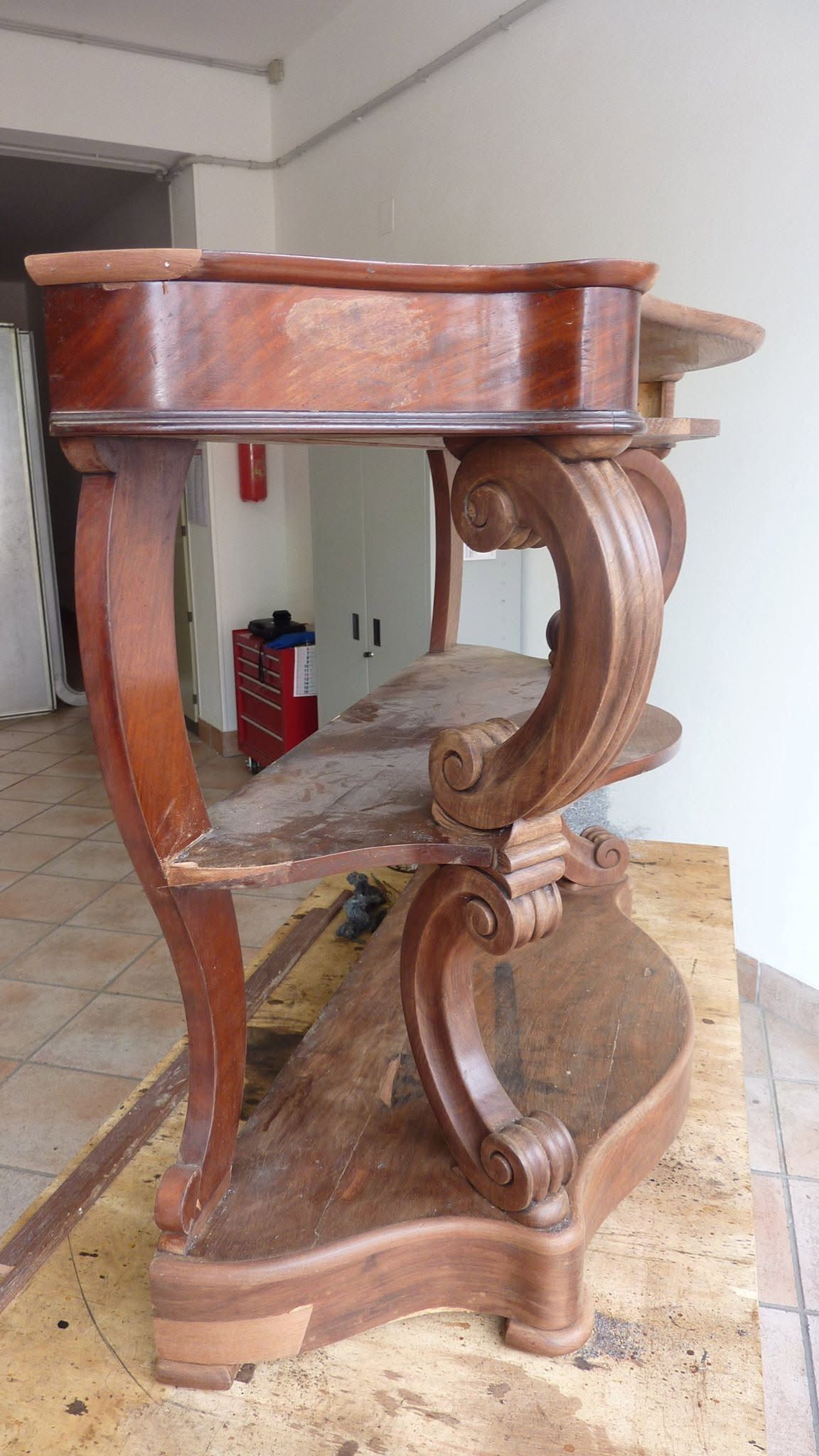 Tavolino laterale in legno intagliato con gambe curve, in una stanza con pavimento piastrellato