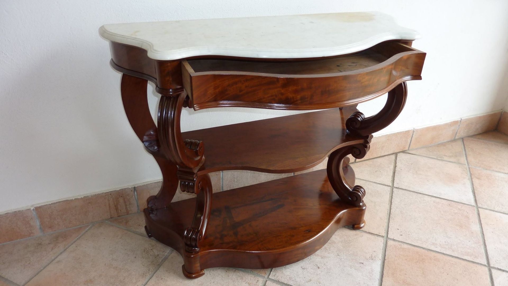 Consolle in legno con piano in marmo bianco su un pavimento piastrellato