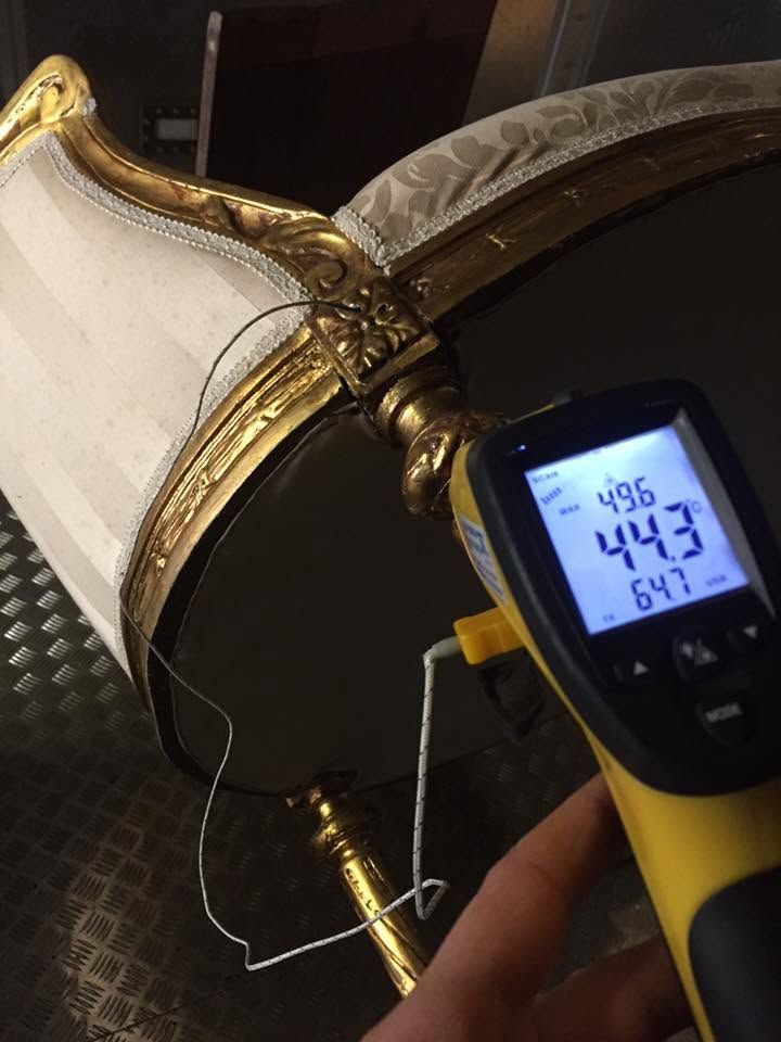 Termometro a infrarossi portatile che misura un paralume bianco e oro, con una temperatura indicata di 44,3 °C