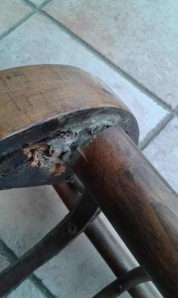 Giuntura rotta di una sedia di legno, con il legno danneggiato e il materiale interno esposto, su un pavimento piastrellato.