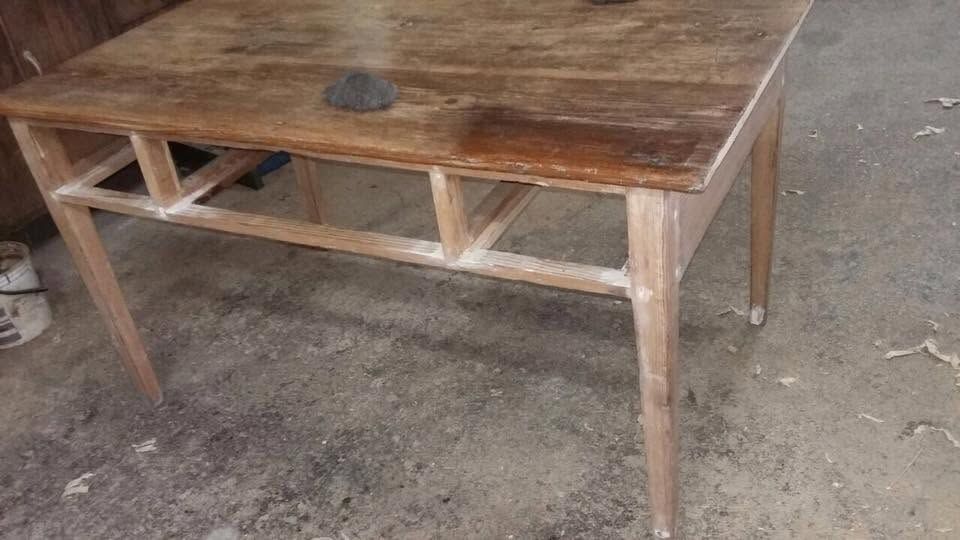 Tavolo rustico in legno con piano scuro e gambe chiare, in un laboratorio o in un garage