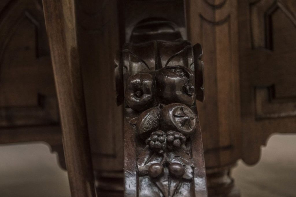 Primo piano di un dettaglio di un mobile in legno intagliato e decorato, con motivi floreali e inserti metallici