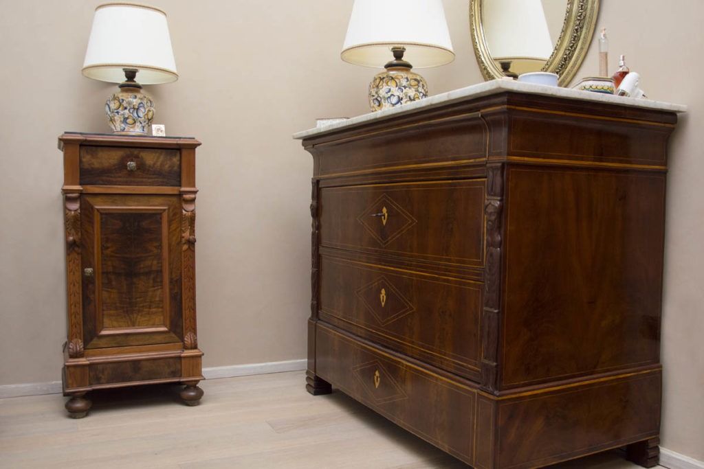 Due armadietti in legno scuro con lampade da tavolo sopra, in una stanza beige