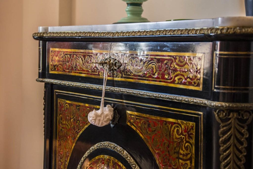 Mobiletto nero e oro decorato, con modanature ornamentali e un piccolo nappa come pomello del cassetto