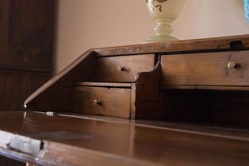 Scomparto aperto di una scrivania in legno con cassettini e un vaso in ceramica sopra