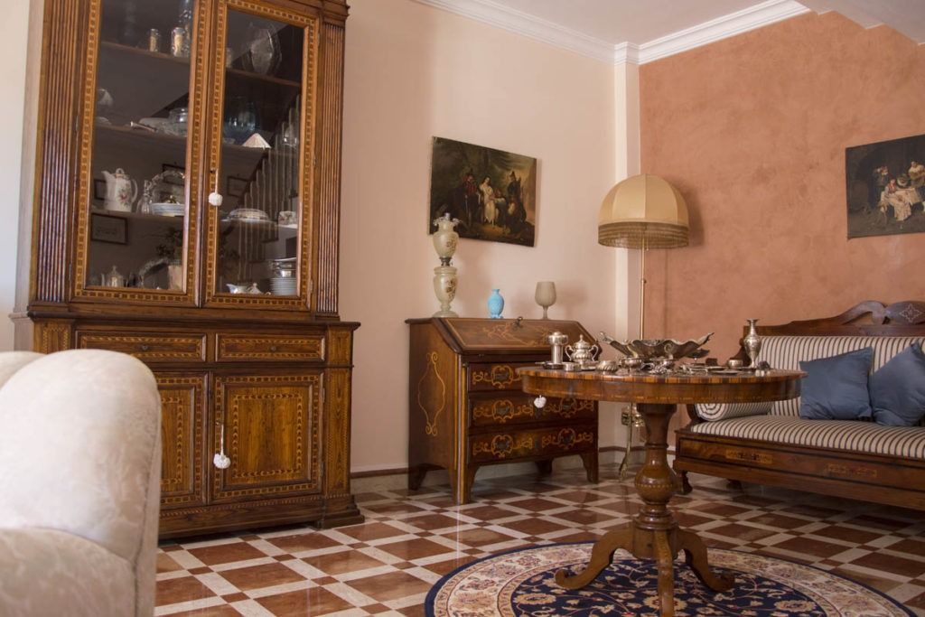 Elegante soggiorno con pareti color pesca, pavimento in piastrelle decorate, mobili in legno scuro e una lampada da tavolo
