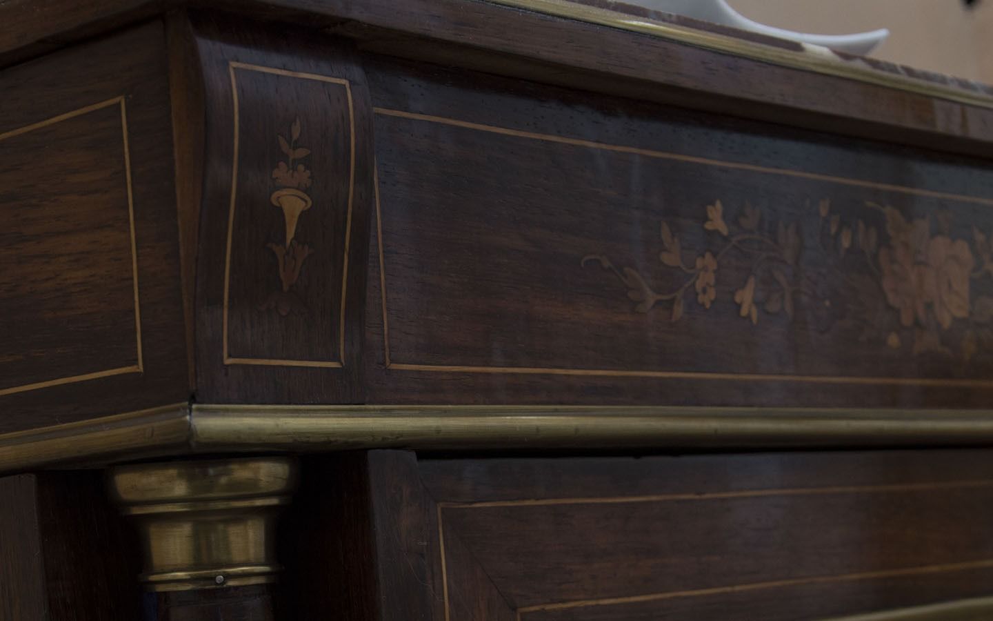 Primo piano di un’antica bara in legno scuro, con finiture in ottone e intarsi decorativi
