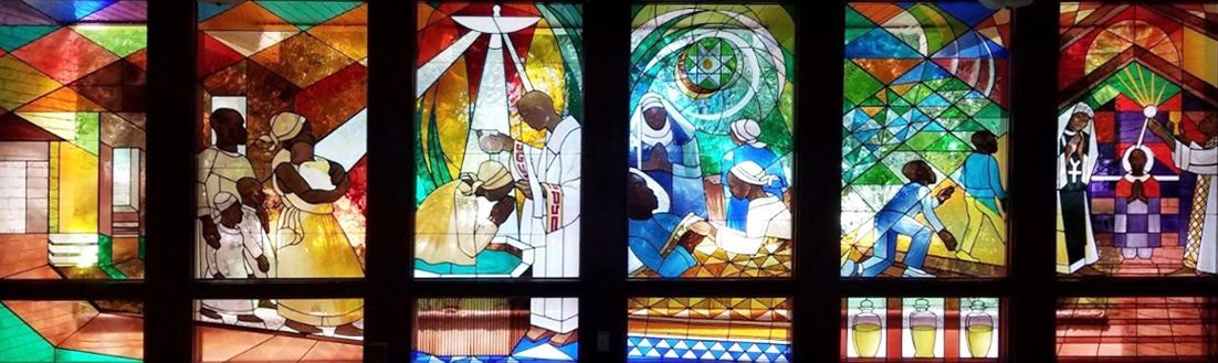 Colorful stained-glass church windows depicting biblical scenes and a central cross