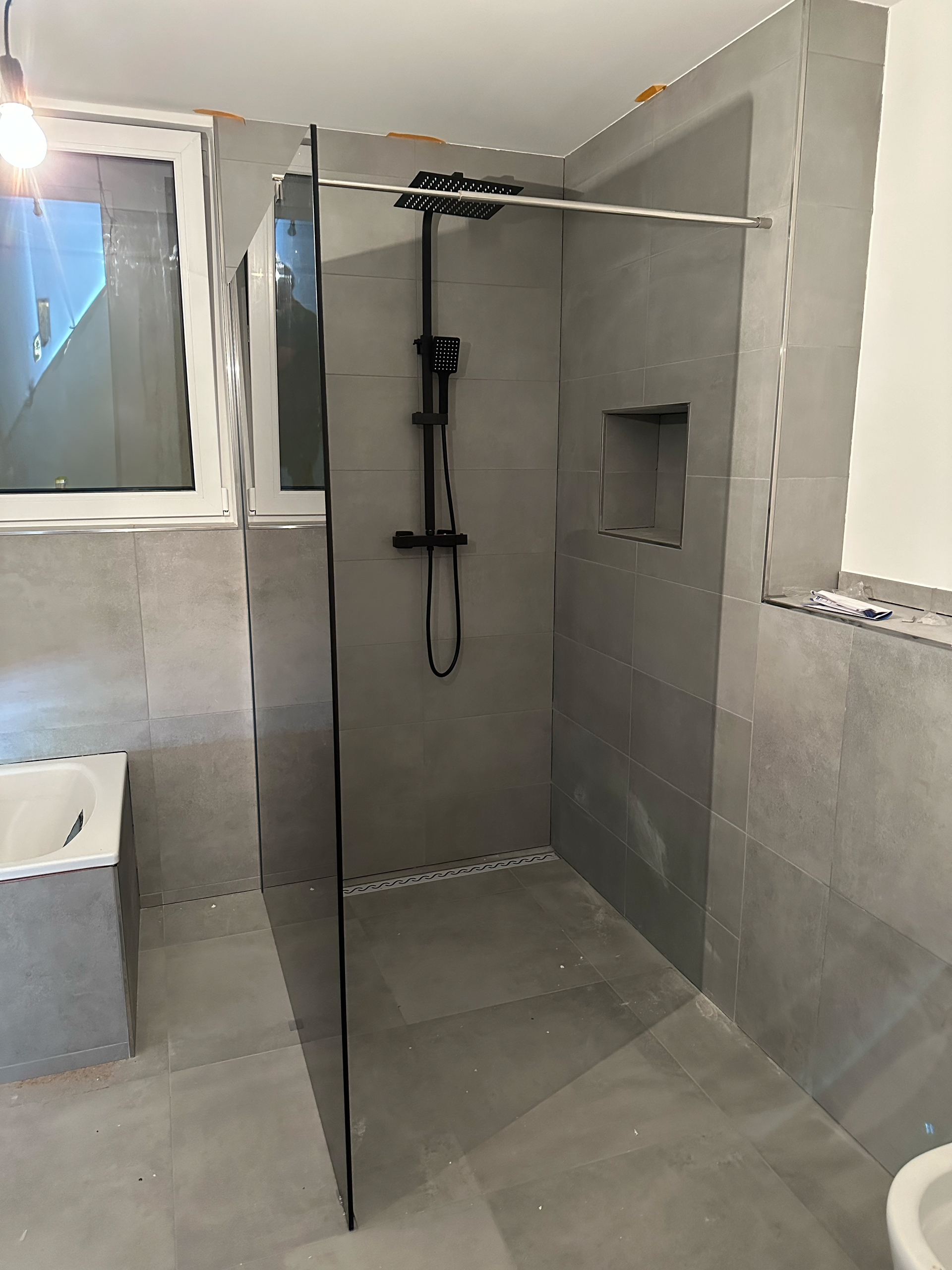 Ein Badezimmer mit ebenerdiger Dusche und Toilette.