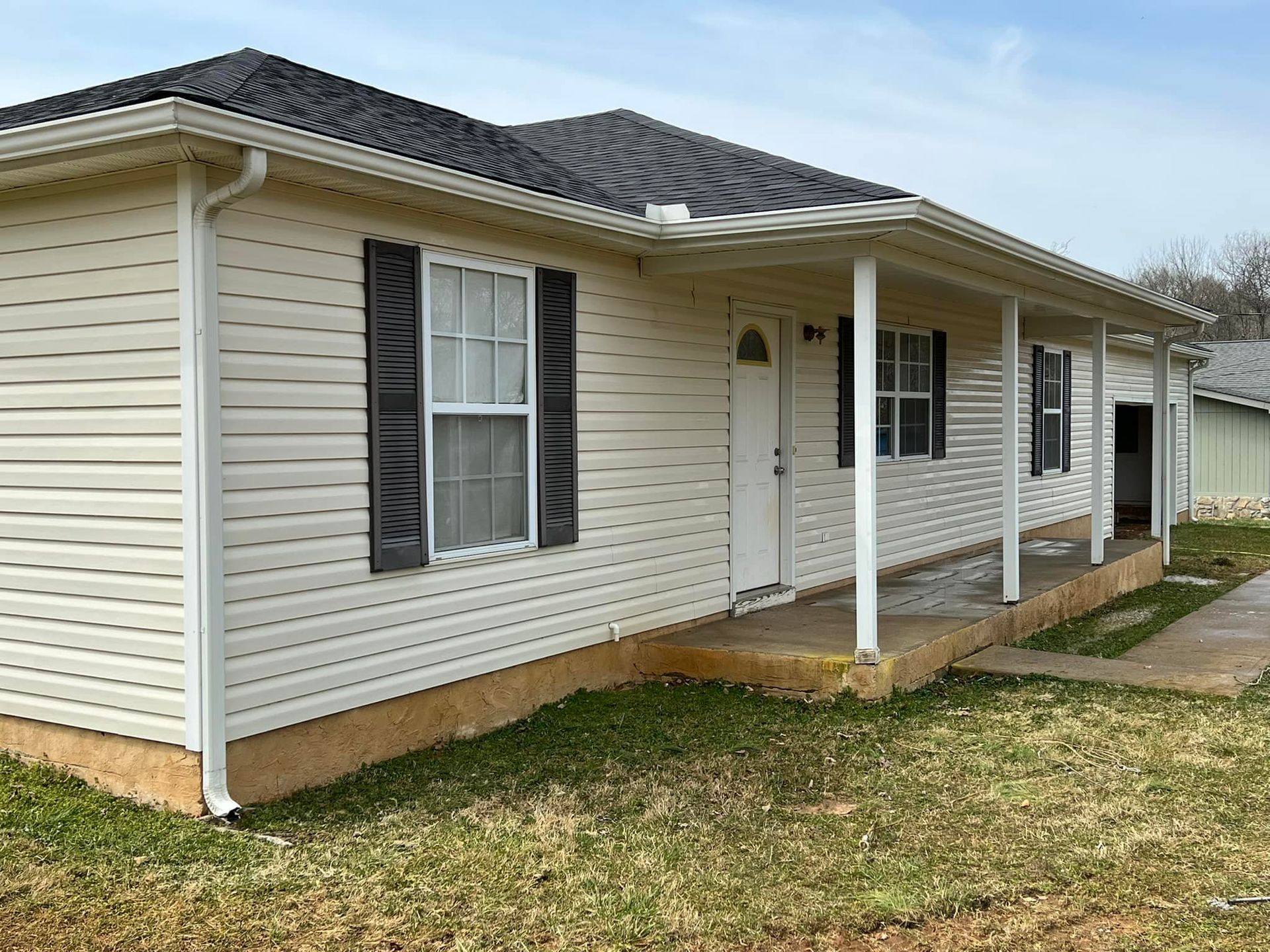 A white house with a porch and black shutters
