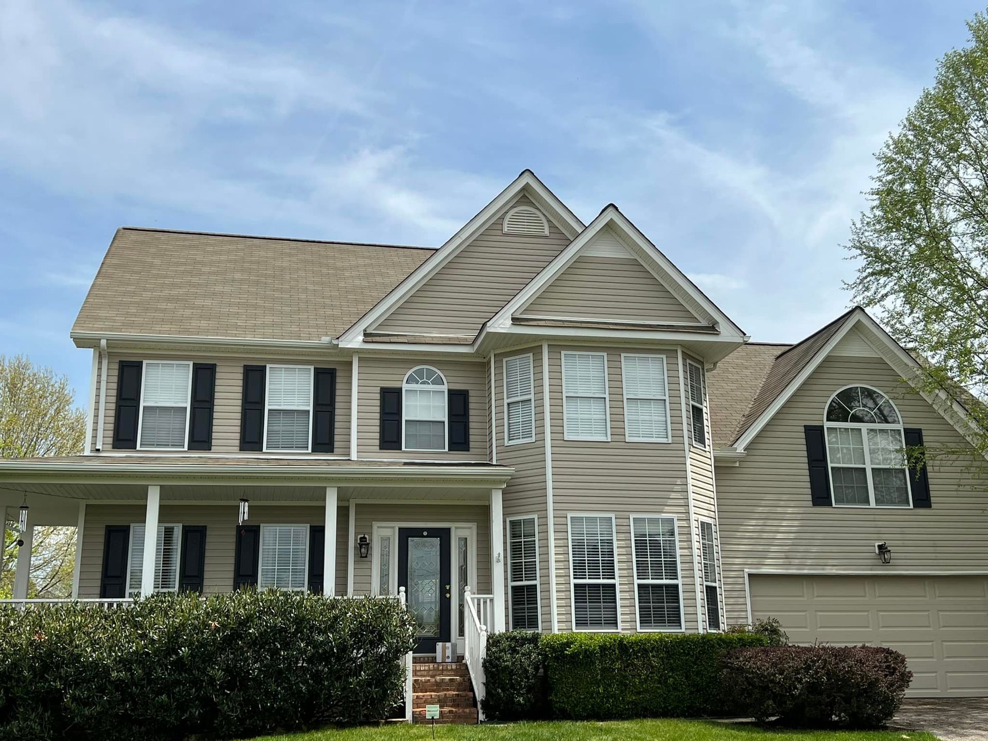 A large house with a lot of windows and black shutters on a sunny day.