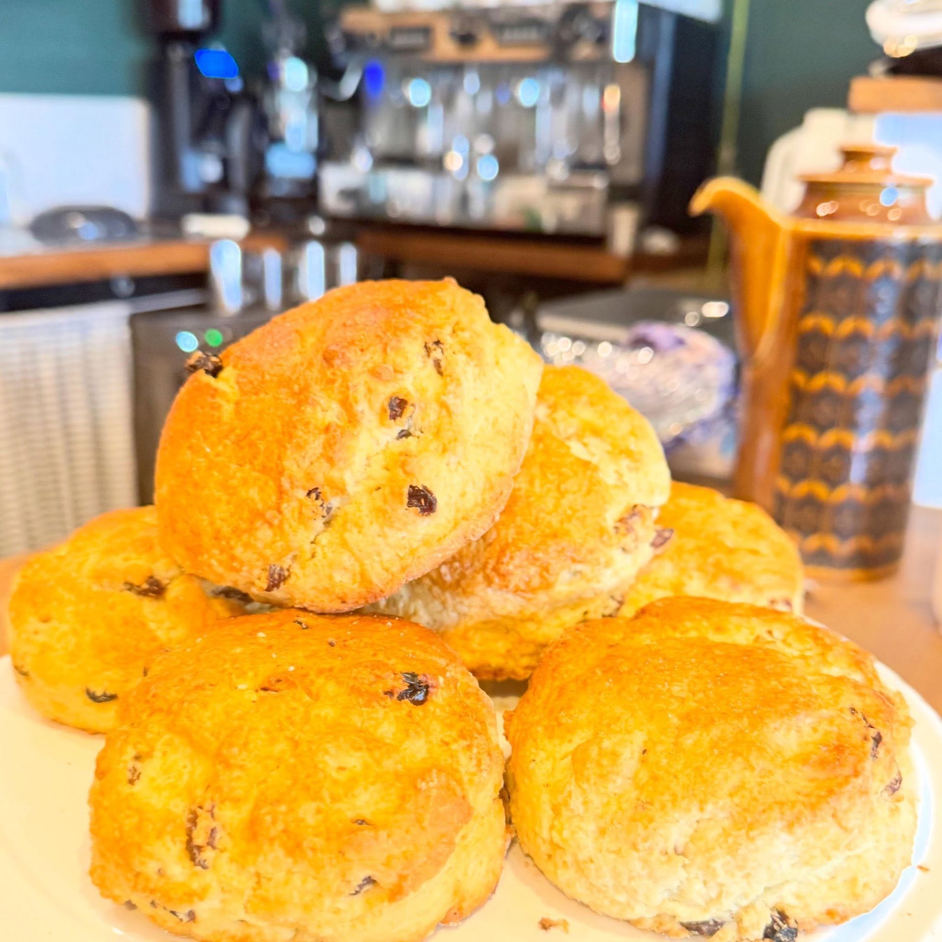 Stack of golden scones on a kitchen counter with a coffee machine blurred in the background