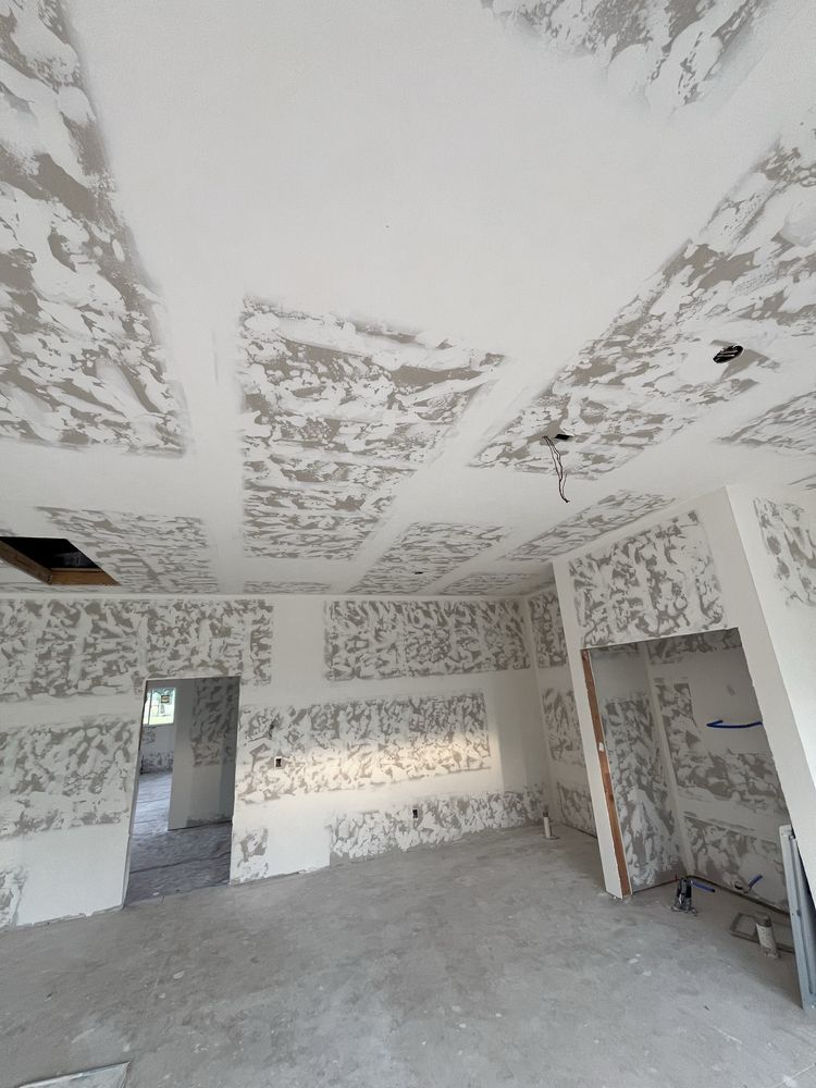 Partially renovated room with plaster-covered walls and ceiling, concrete floor, and a doorway to another room