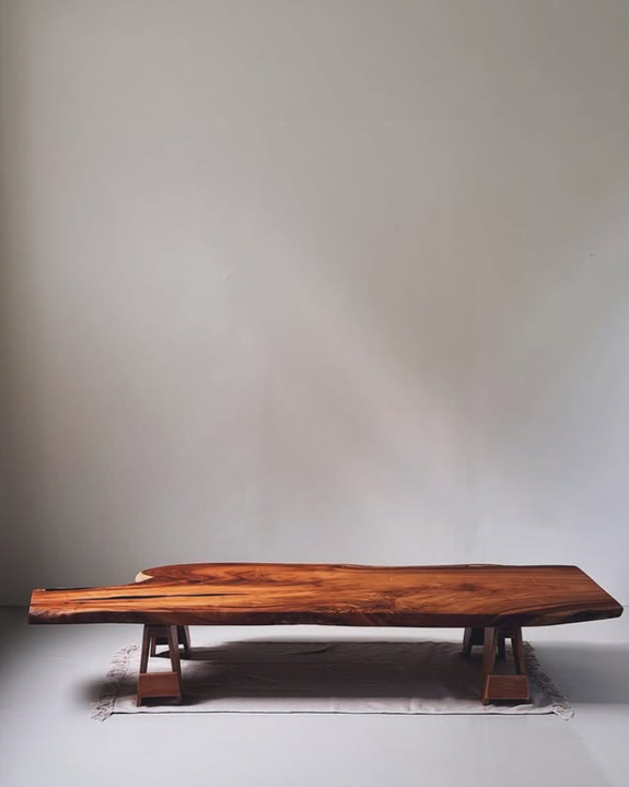 A zen wooden bench is sitting on the floor in front of a white wall.
