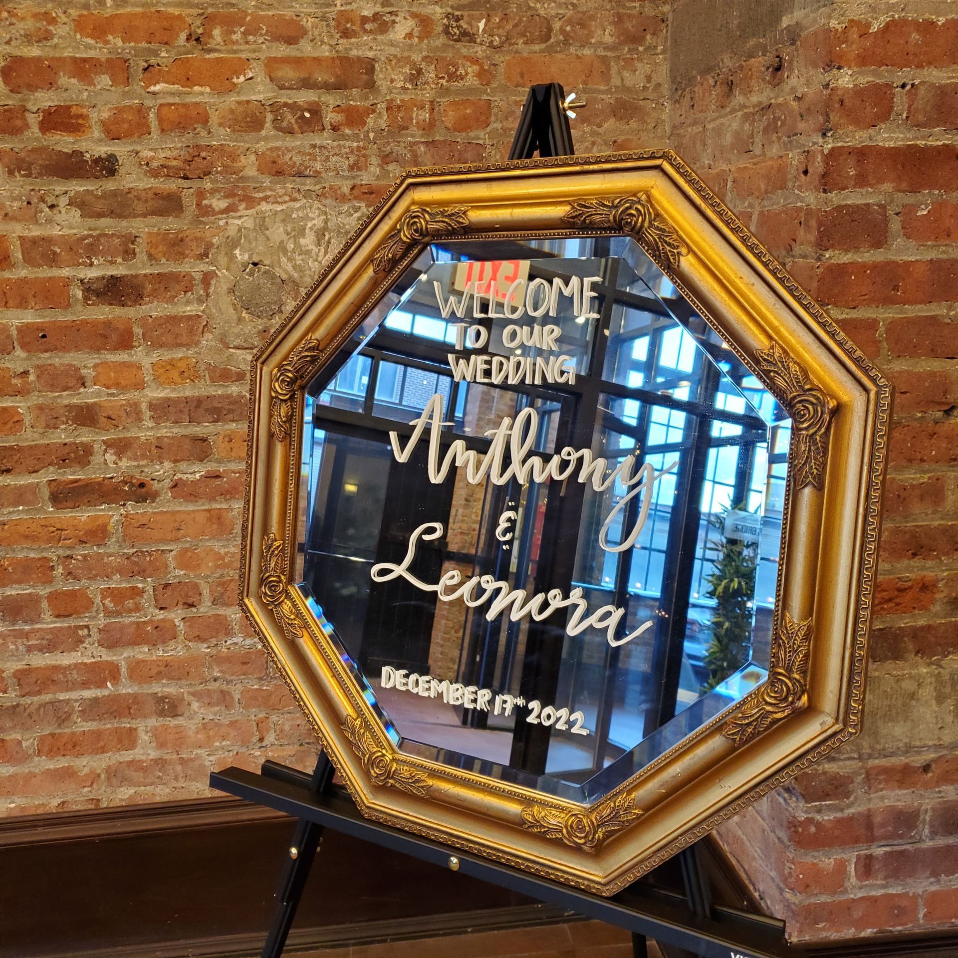 An octagonal gold-framed mirror on an easel, inscribed with 