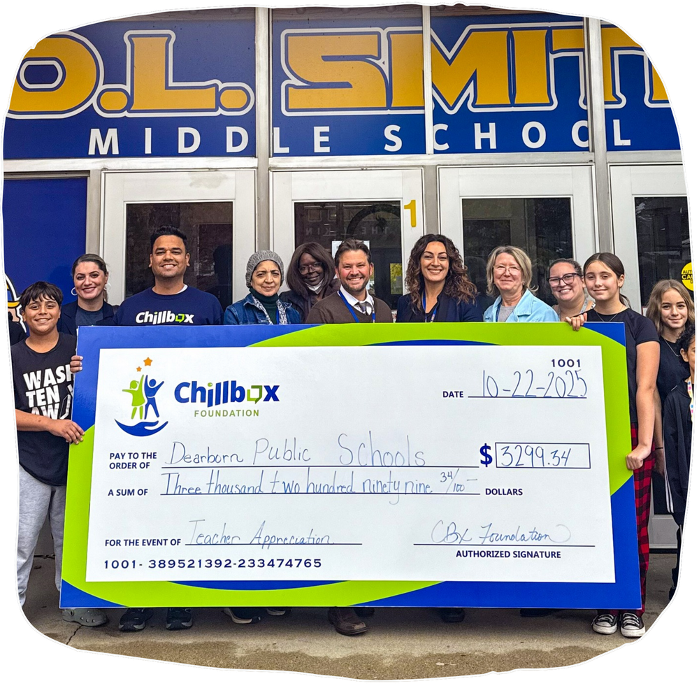 Group of people holding a giant ChilliBox check outside O.L. Smith Middle School