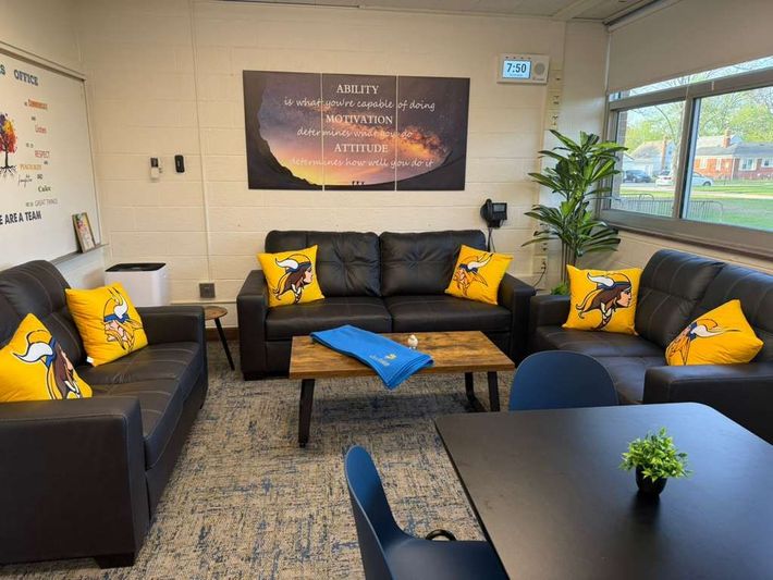 Cozy lounge with black sofas, yellow pillows, blue cushions, a table, plant, and wall art