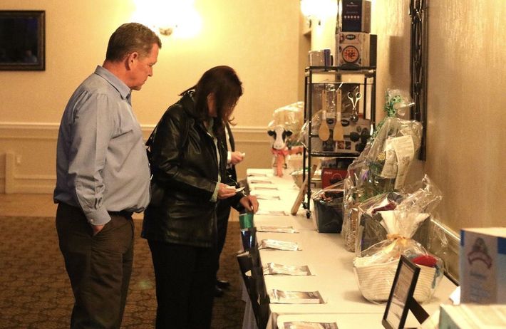 Two people inspecting items displayed on a long table in a warmly lit room