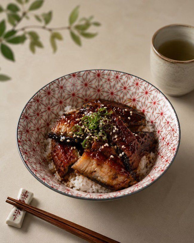 Glazed grilled fish in a patterned bowl with chopsticks and a cup of tea
